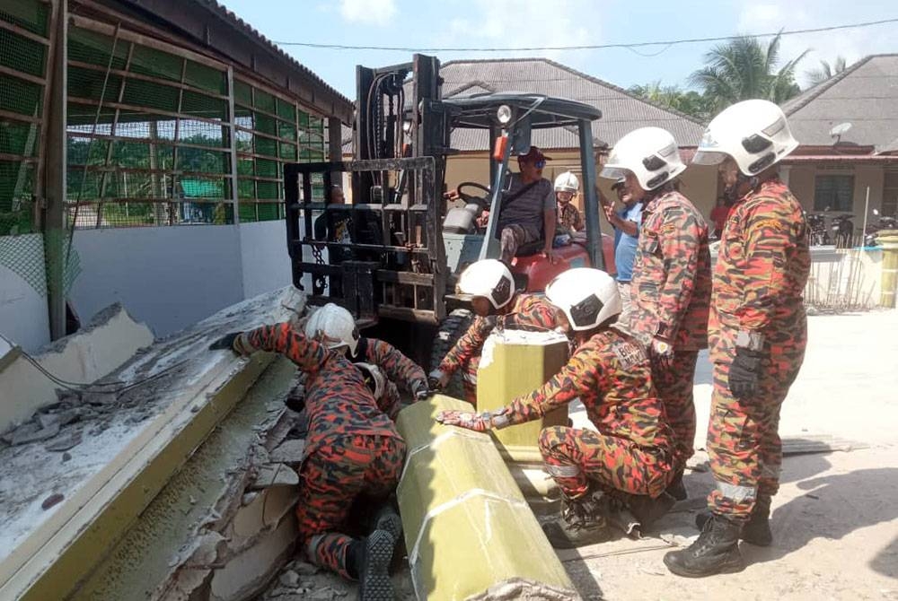 Anggota bomba cuba mengeluarkan mangsa yang tersepit. - Foto JBPM