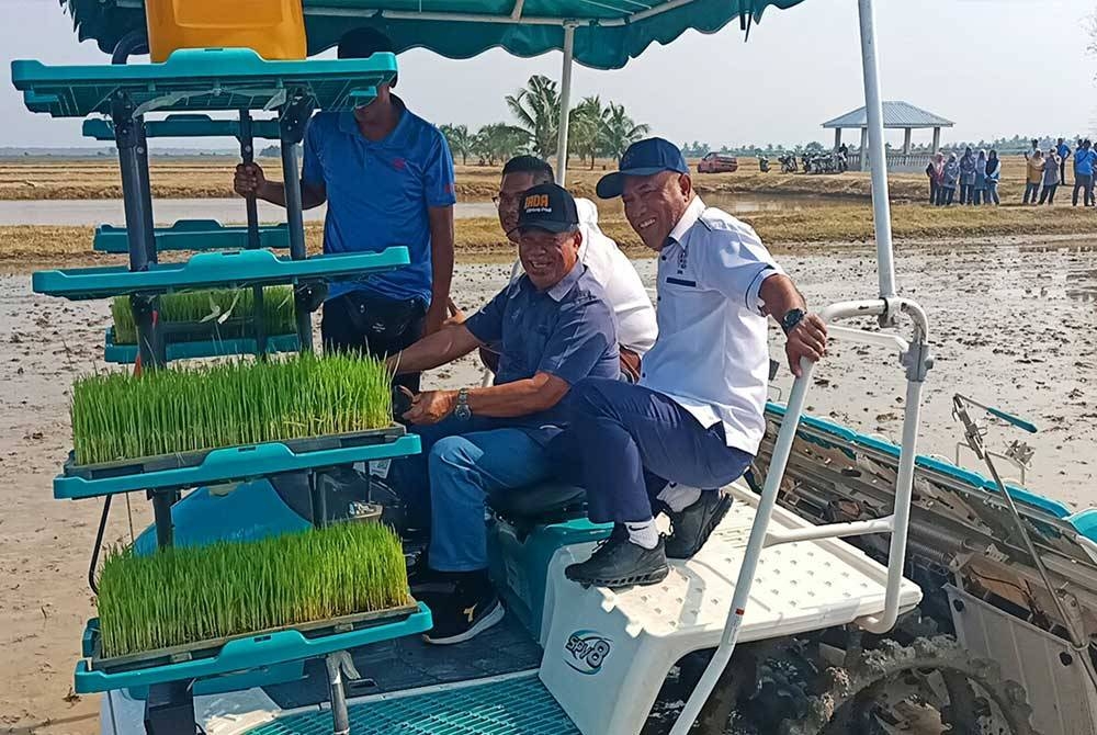 Mohamad (dua dari kanan) melakukan demo menanam padi menggunakan jentera penanam padi (transplanter) sempena lawatannya ke Ladang Kekal Pengeluaran Benih Padi Felcra di Seberang Perak, pada Jumaat.