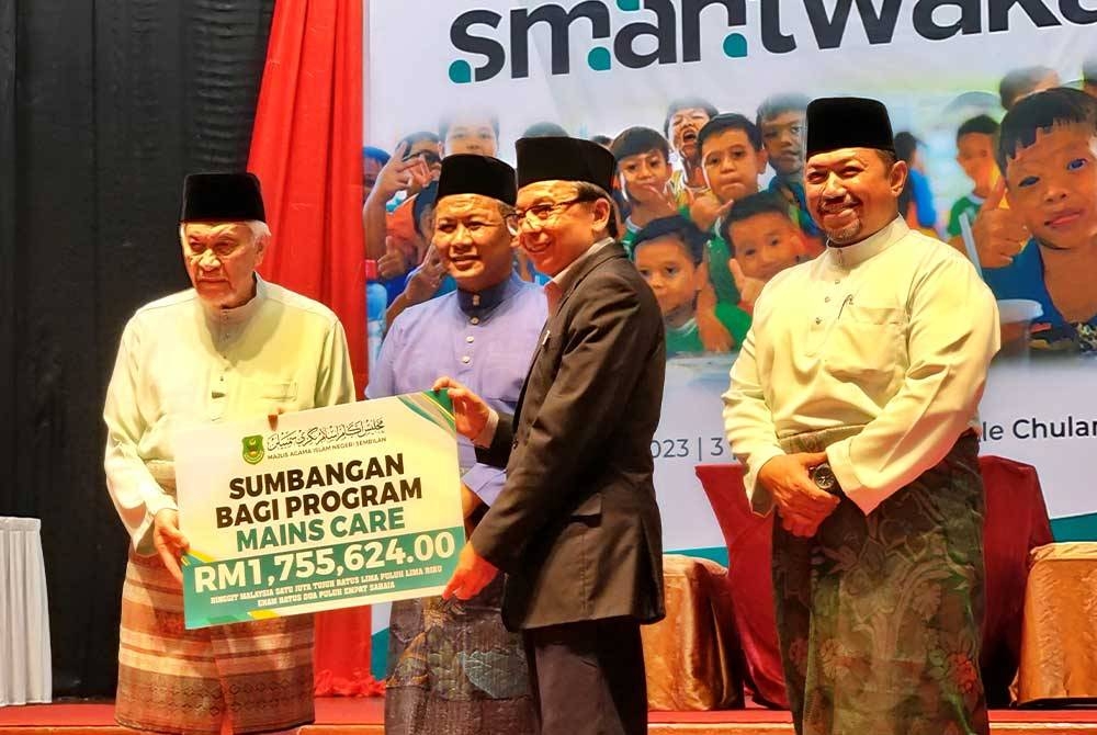 Abdul Aziz (kiri) menyerahkan replika cek sumbangan program MAINS Care kepada Roslan (dua dsri kanan). Turut kelihatan Aminuddin (dua dari kiri)