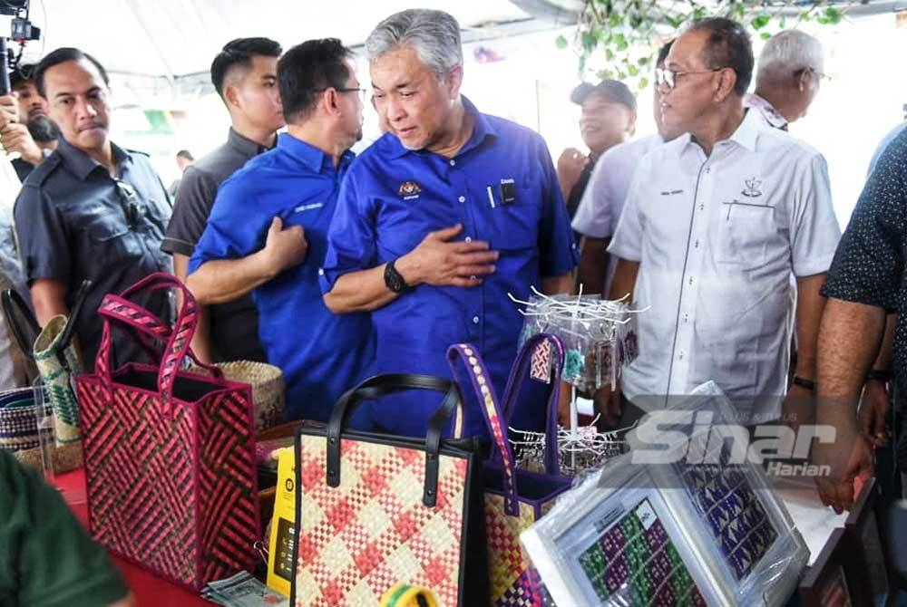 Ahmad Zahid (tengah) bersama Wan Rosdy ketika melawat pameran sempena program Sentuhan Kasih Desa Pelangai Mini Ekspo TVET KKDW dan Keusahawanan Desa di Dataran Simpang Pelangai pada Sabtu.