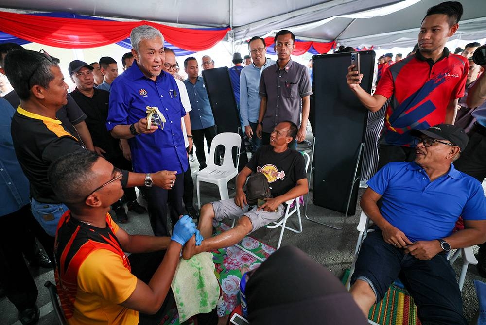 Ahmad Zahid beramah mesra dengan pelanggan yang mendapatkan perkhidmatan refleksologi yang ditawarkan secara percuma pada program Sentuhan Kasih Desa @ Simpang Pelangai - Mini Karnival Usahawan Desa & Mini Ekspo TVET @ Kementerian Kemajuan Desa dan Wilayah (KKDW) pada Sabtu. - Foto: Bernama