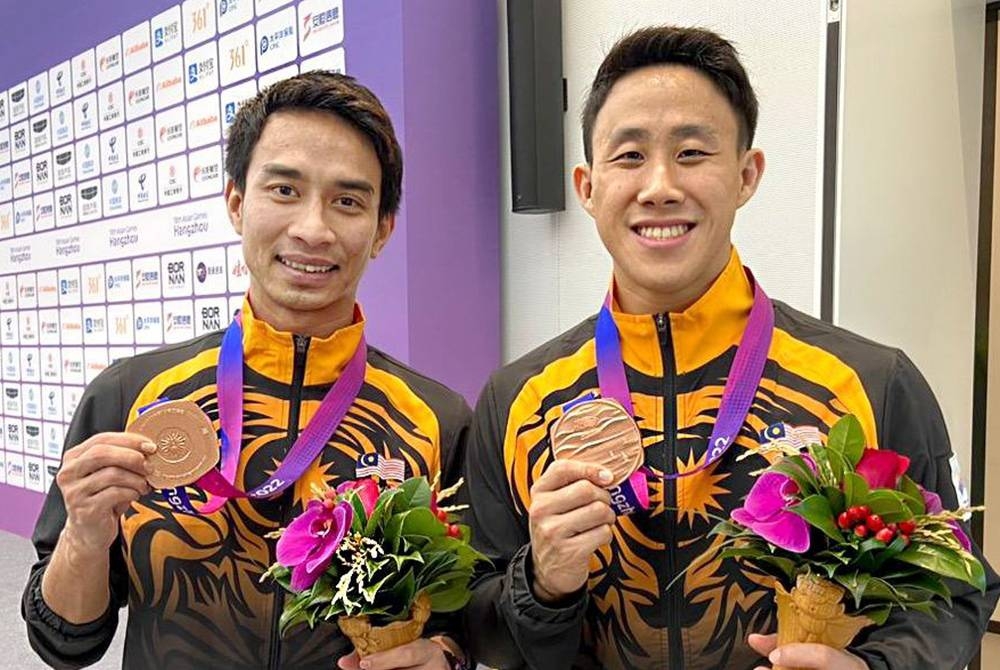 Muhammad Syafiq (kiri) dan Tze Liang berjaya meraih pingat gangsa kedua buat kem terjun negara di Arena Sukan Akuatik, Pusat Sukan Olimpik Hangzhou. - Foto: Bernama