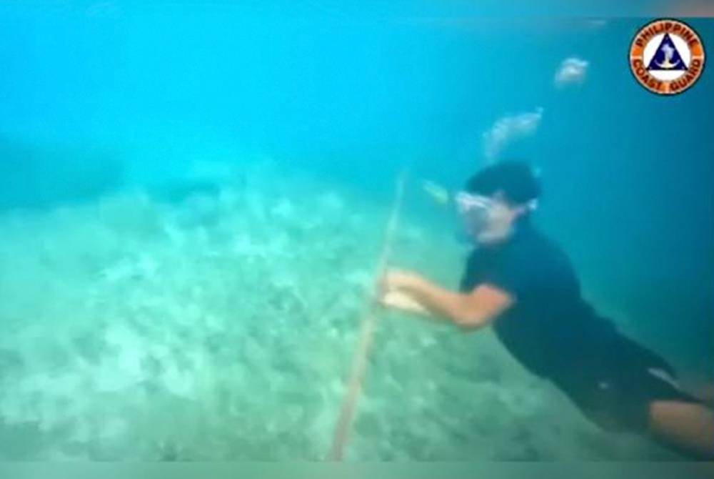 Dalam paparan video tersebut, seorang penyelam dilihat terjun dan berenang di bawah permukaan air ke tali yang diletakkan di salah satu hujung pelampung. - Foto ihsan Pasukan Pengawal Perairan Filipina