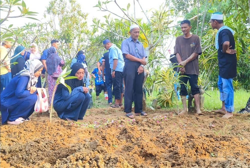 Abu Bakar (tiga dari kanan) ditemui pengebumian anak kelimanya di Tanah Perkuburan Islam Keluarga Haji Talib Kampung Paya Tengah, Beseri, Padang Besar pada petang Ahad.