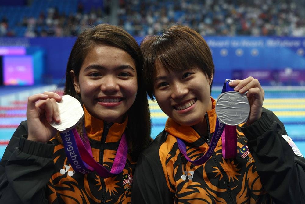 Nur Dhabitah dan Wendy Ng selepas meraih pingat perak dalam acara 3m papan anjal seirama wanita akhir pada Sukan Asian Hangzhou 2022 di Arena Sukan Akuatik Pusat Sukan Olimpik Hangzhou pada Ahad.