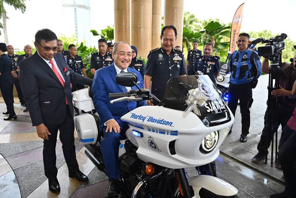 Hajiji (tengah) menaiki motosikal berkuasa tinggi Harley Davidson diiringi Jauteh (kanan) dan Safar (kiri) ketika majlis penyerahan kenderaan itu di pekarangan Menara Kinabalu pada Selasa.