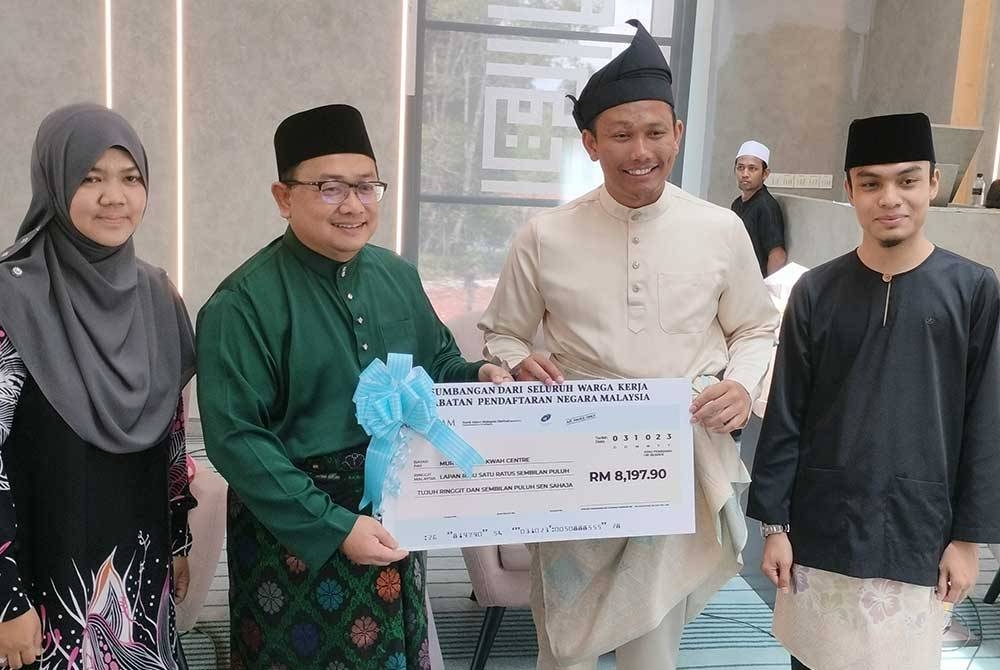 Zamri (dua kiri) menyampaikan replika cek kepada Mohammad Yaakub Yusra sempena Sambutan Hari Jabatan Pendaftaran Negara kali ke-75 di Murthada Dakwah Centre (Madad) di Kampung Telok, di sini, pada Selasa.