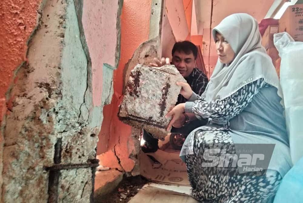 Dr Hafidzah (kanan) mengangkat bongkah batu yang jatuh dalam kejadian di tingkat satu Pasar Siti Khadijah pada Isnin.