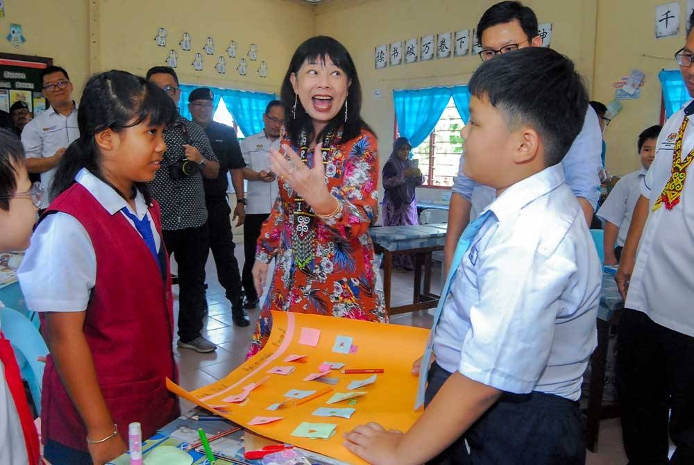 Hui Ying (tengah) menyantuni murid-murid ketika melakukan lawatan kerja ke Sekolah Jenis Kebangsaan (C) Bulat, Sarikei pada Isnin. - Foto Bernama