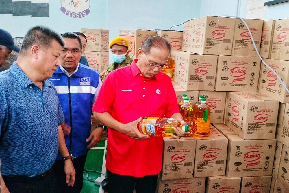 Wan Rosdy (kanan) ketika melihat minyak botol yang dijual di Jualan Makmur Pahang di Dewan Serbaguna Kampung Chemomoi, Bentong pada Selasa