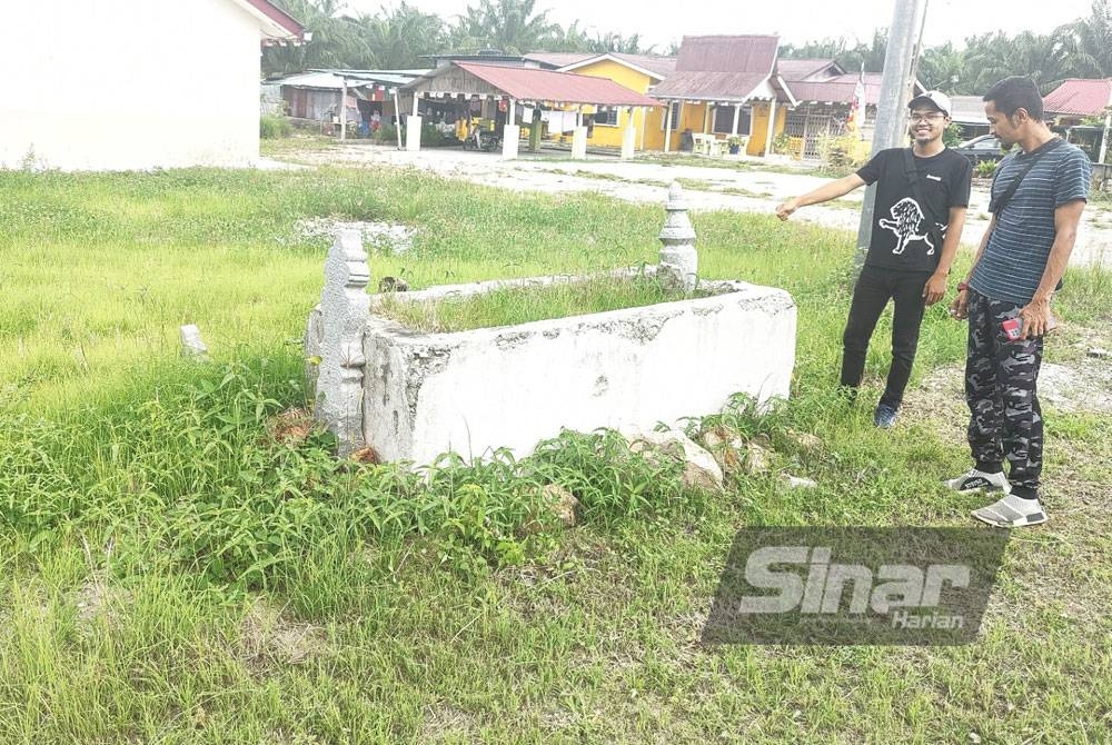 Muhammad Fariz (kiri) menunjukkan sebuah kubur lama di tepi jalan di Kampung Permatang Tengah.