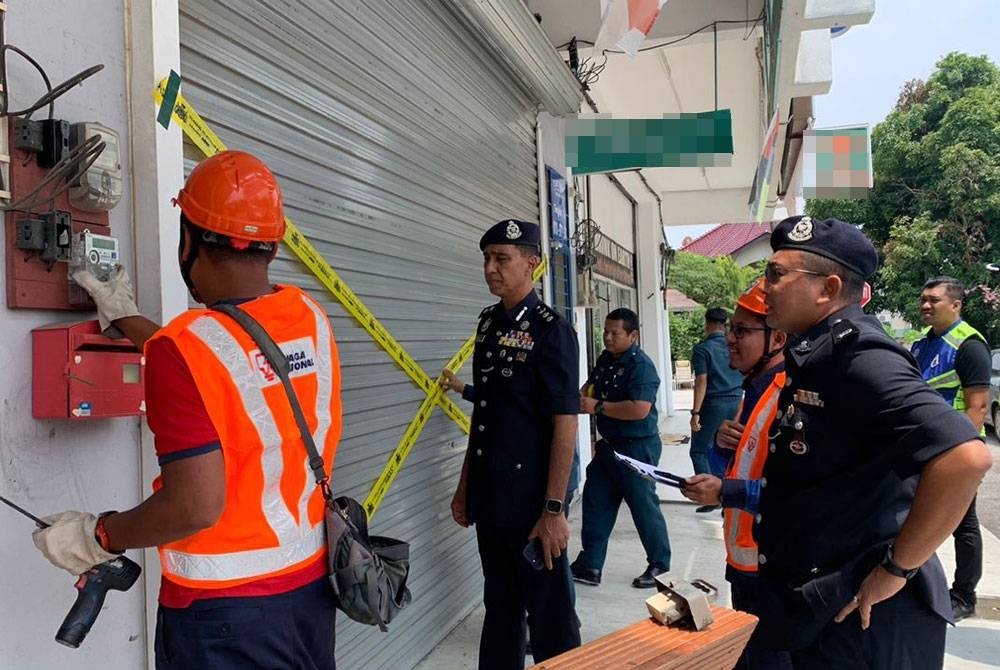 Raiz Mukhliz (tengah) melihat sebuah premis dipotong bekalan elektrik dan disita dalam Ops Dadu di Bandar Muar, Muar pada Selasa.