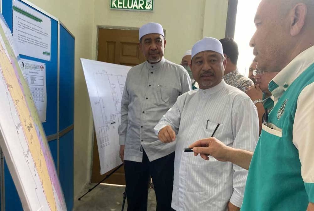 Dr Izani (kiri) dan Mohd Nassuruddin (tengah) mendengar taklimat semasa Majlis Perasmian Loji Rawatan Air Mini Meranti Baharu di Pasir Mas pada Rabu.