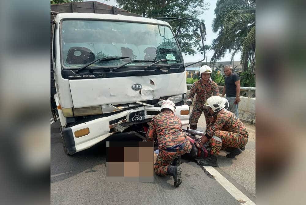 Anggota bomba cuba mengeluarkan mangsa kemalangan dari bawah lori. - Foto BBP Renggam