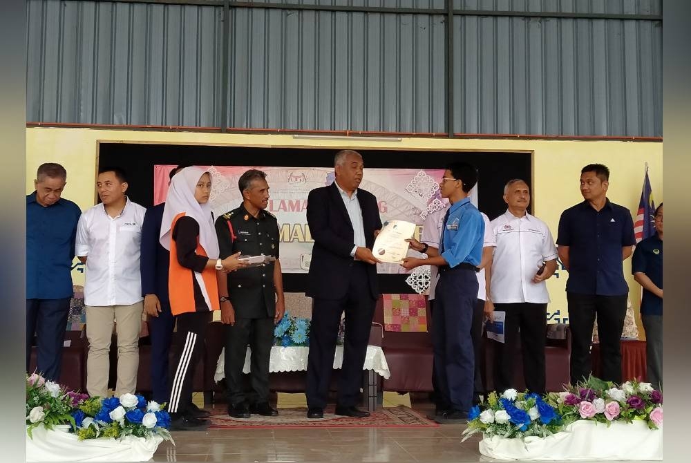 Khairudin (tengah) menyampaikan sijil kepada pelajar SMK Malim Nawar ketika hadir ke Program Penyerahan 30 Unit Laptop oleh Syarikat Maxis Berhad di SMK Malim Nawar di sini pada Rabu.