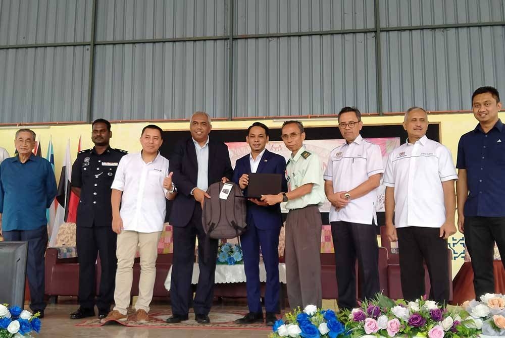 Mohd Azlan (tengah) menyampaikan sumbangan komputer riba kepada wakil sekolah ketika Majlis Penyerahan Laptop dan Program E-Kelas Melalui CSR Maxis Berhad di SMK Malim Nawar, di sini pada Rabu.