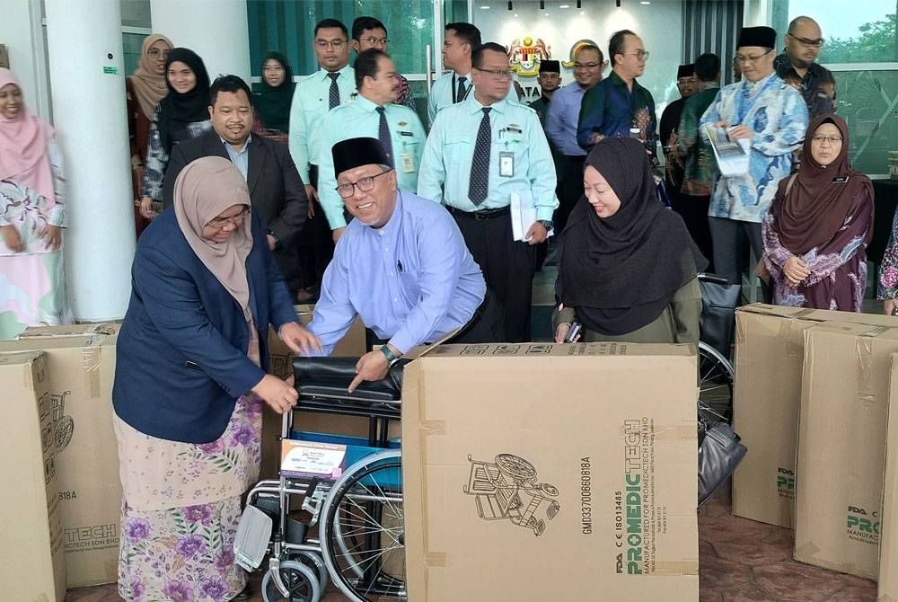 Halidan menyerahkan kerusi roda kepada Dr Nor Azimi sebagai simbolik Majlis Penyerahan Sumbangan Kerusi Roda Wakaf Pahang, Muip dengan Kerjasama Bank Muamalat kepada JKNP, di sini pada Khamis.