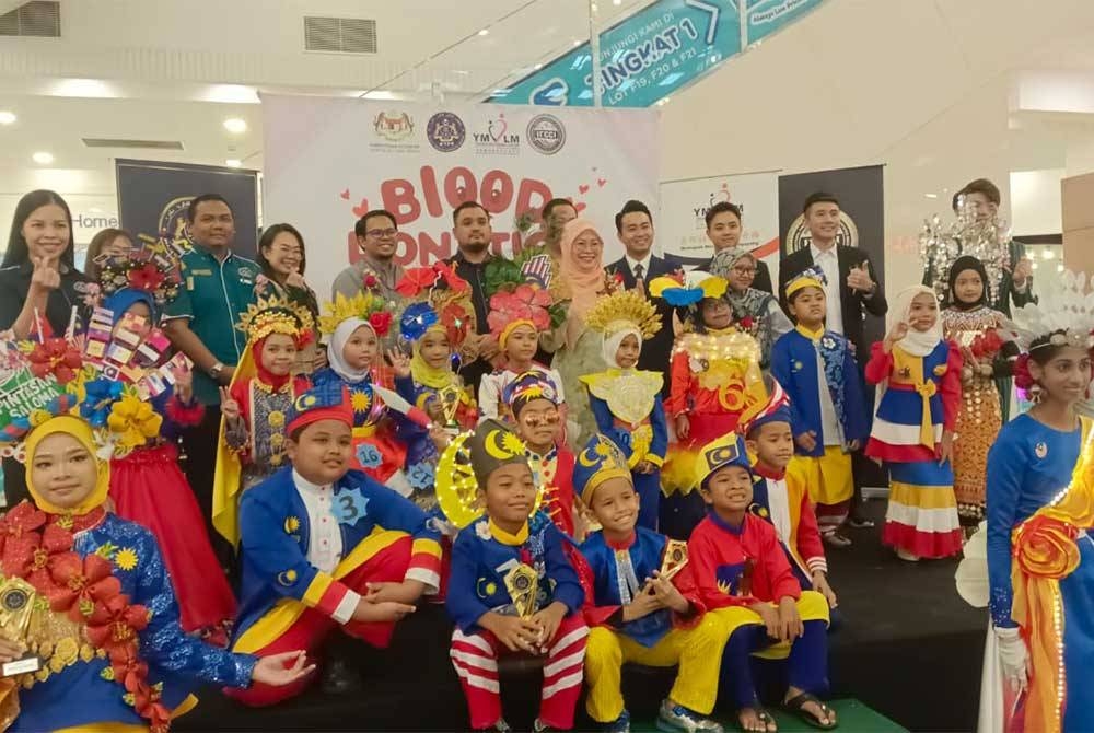 Masrudi (belakang, tengah) dan Enny Suhailis (belakang, lima dari kanan) serta Noorman (belakang, tiga dari kiri) bersama peserta pakaian beragam dalam Kempen Bazar Amal dan Kempen Derma Darah di pusat beli belah AEON Mall Kulaijaya, Kulai pada Jumaat.