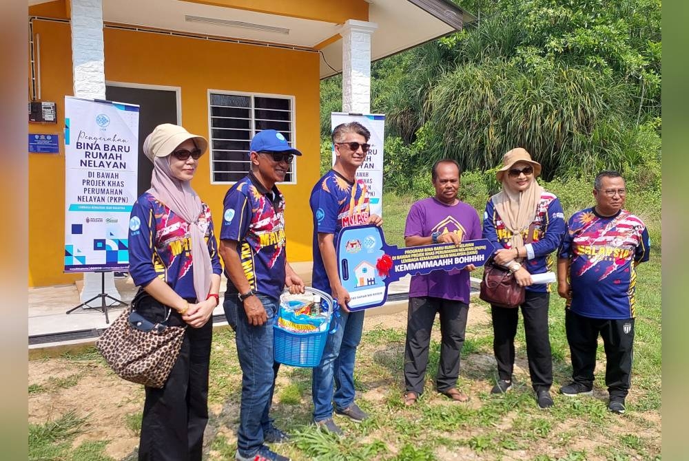 Muhammad Faiz (tiga dari kiri) menyerahkan kunci kepada nelayan Mohd Sapian (tiga dari kanan)