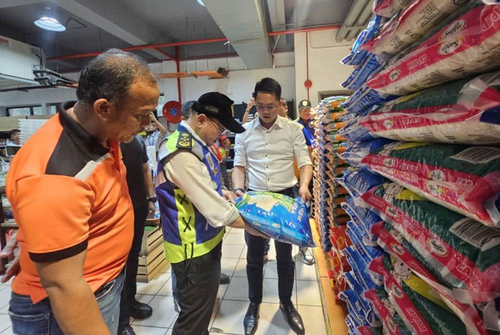 Foong Hin (tengah) memeriksa harga beras putih import yang kini dijual di pasaran dengan harga baharu di Sabah.