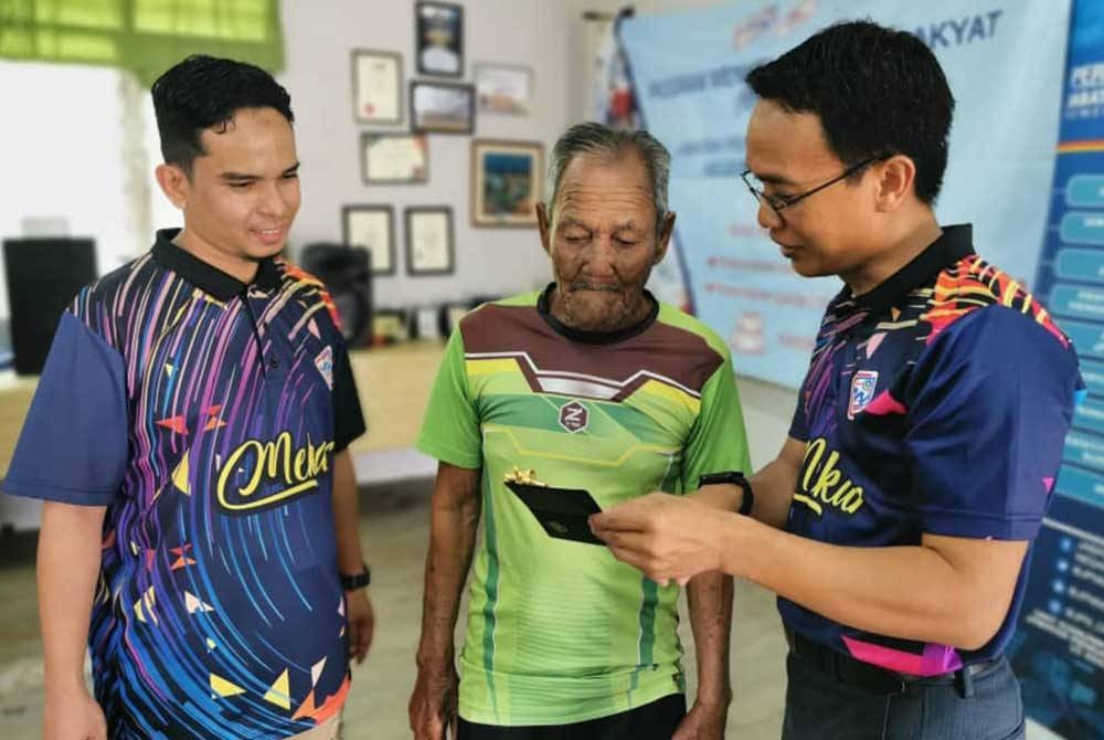 Mohamad Nasir (kanan) beramah mesra dengan Rj Abdullah (tengah) selepas Program Mekar Komuniti: Penyerahan Dokumen Pengenalan Diri di Pulau Redang di sini