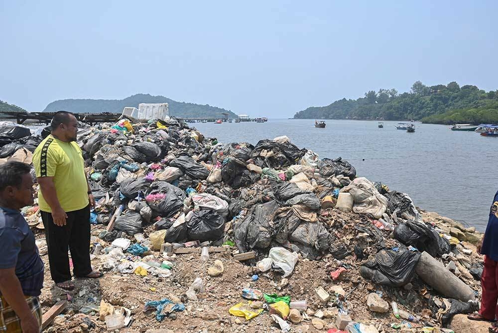 Johasman (dua dari kiri) menunjukkan sampah yang tidak dikutip berdekatan bangsal nelayan Kampung Baru Pulau Redang.