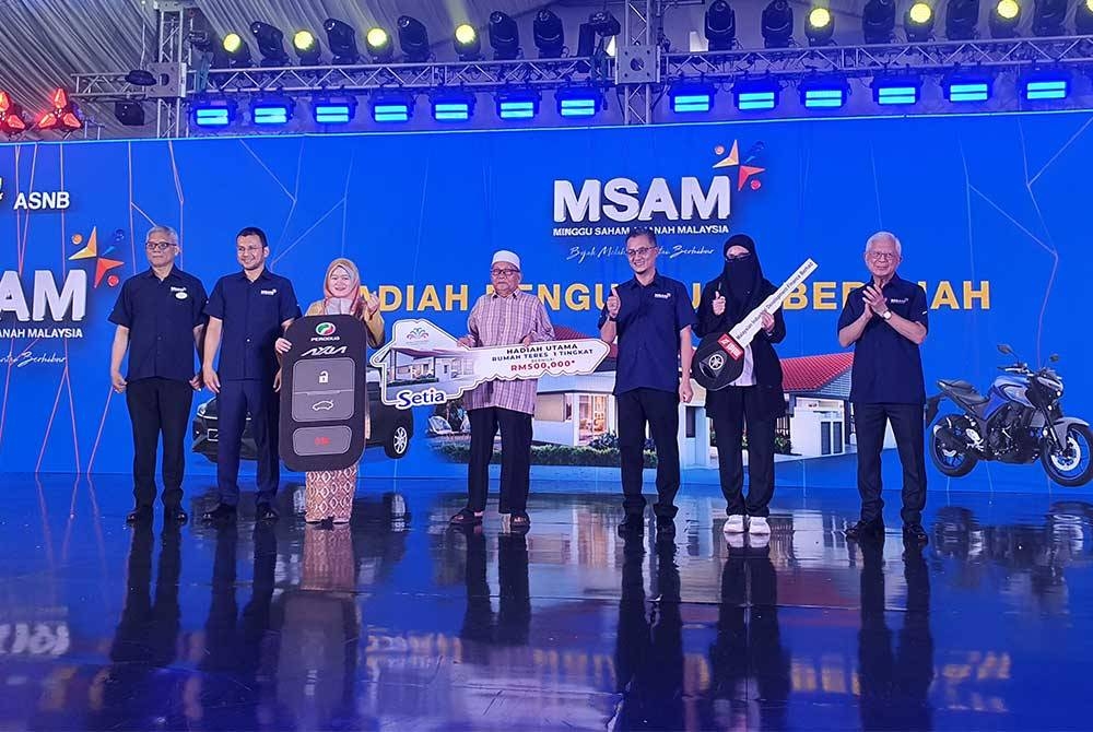 Mohamad (tiga dari kanan) dan Arshad (kanan) bergambar bersama tiga pemenang hadiah utama MSAM termasuk sebuah rumah teres bernilai RM500,000, sebuah kereta dan motosikal.