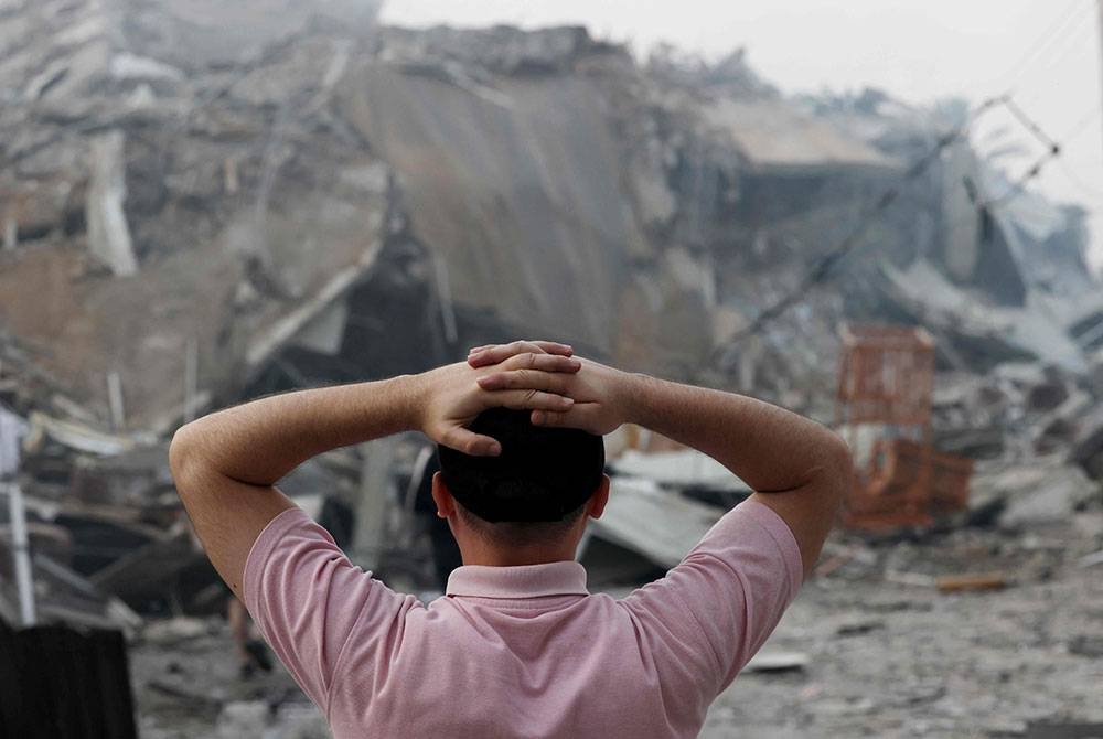 Seorang lelaki Palestin berdiri di hadapan runtuhan Menara Al-Watan Kota Gaza, yang musnah dalam serangan udara Israel. Foto AFP