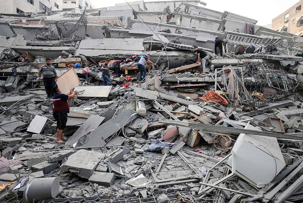 Penduduk menyelamatkan beberapa barang dari bangunan yang runtuh semasa serangan udara Israel. Foto AFP