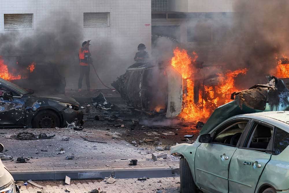 Beberapa buah kenderaan di Ashkelon rosak teruk akibat terkena bedilan roket Hamas pada Sabtu. - Foto: AFP