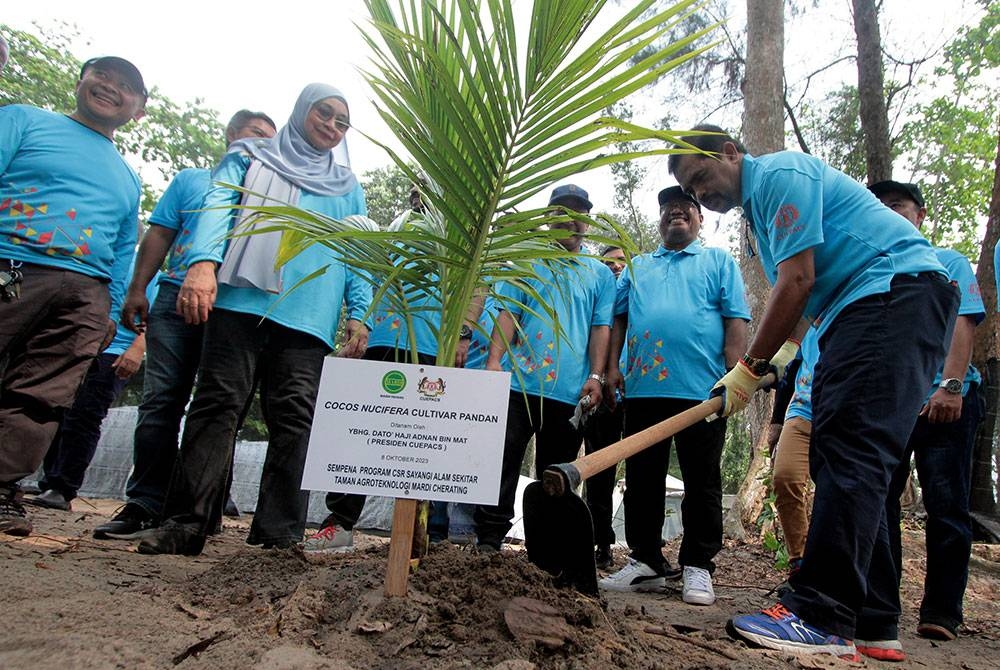 Adnan (kanan) menanam pokok kelapa Pandan simbolik perasmian Seminar Kepimpinan Wanita, Jati Diri dan CSR Cuepacs negeri Pahang di Taman Agroteknologi Mardi Cherating. - Foto Bernama