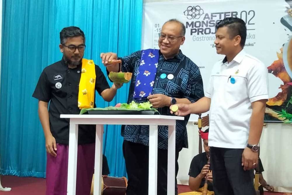 Amerudin (tengah) menuang budu ke dalam tempurung kelapa yang dipegang Azzahar sebagai simbolik perasmian Program After Monsoon Project 02, Gastronomi Langkasuka &#039;Bekwoh Langkasuka di sini pada Ahad.