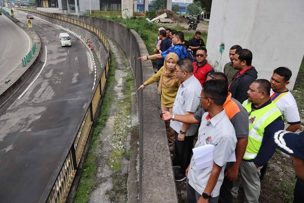 Kamarulzaman (dua dari kanan) meninjau antara jalan ditakungi air susulan hujan lebat pada Jumaat.