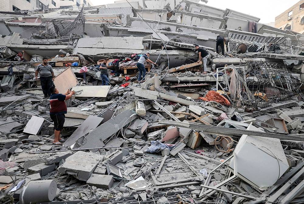 Penduduk menyelamatkan beberapa harta benda dari bangunan yang runtuh semasa serangan udara Israel di Gaza City. - Foto AFP