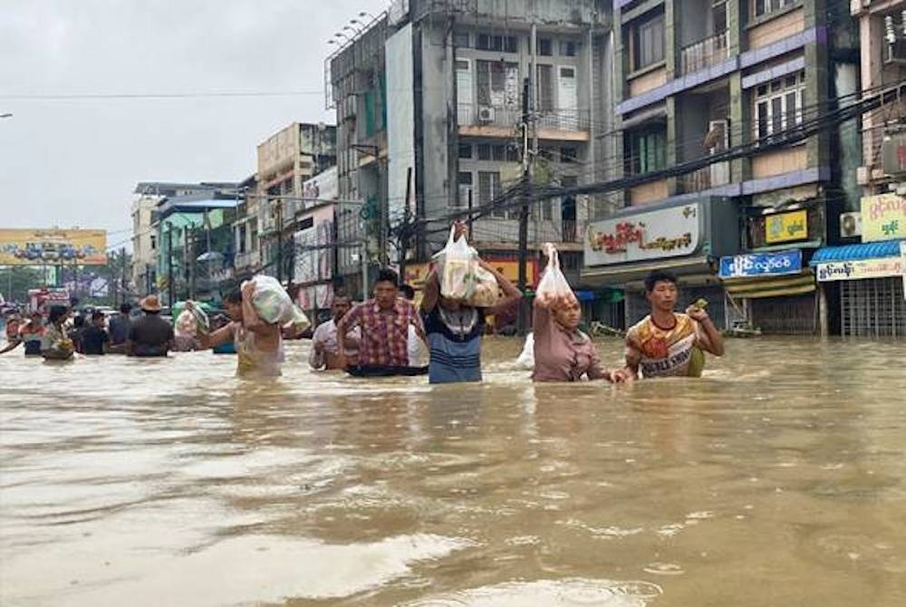 Penduduk tempatan terpaksa meredah air banjir selepas jalan utama di Bago ditenggelami pada Selasa. - Foto AP