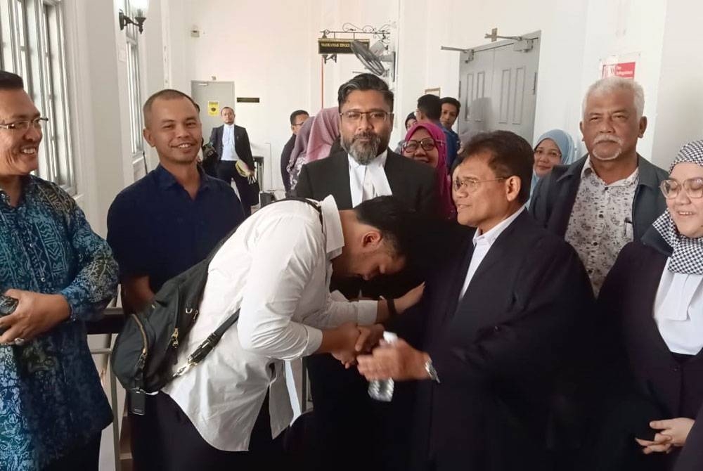 Ahmad Fauzan (depan, kiri) bersalam dengan Salehudin selepas Mahkamah Tinggi Johor Bahru pada Rabu mengekalkan keputusan melepaskan dan membebaskannya daripada tuduhan pengubahan wang haram.