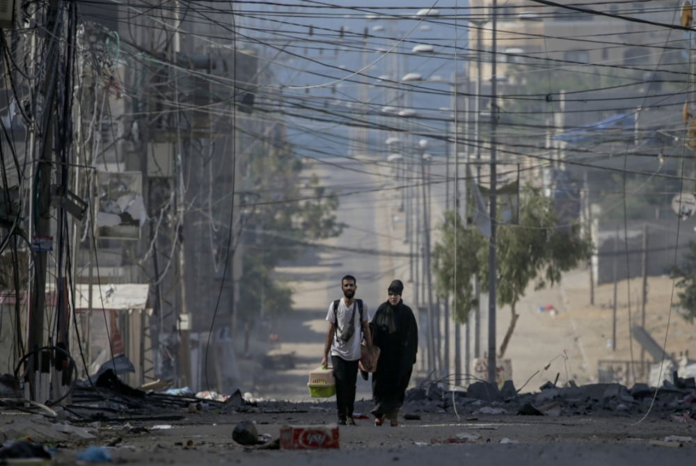 Kelihatan seorang lelaki dan wanita Palestin sedang berjalan meninggalkan kawasan susulan serangan udara Israel di barat kem pelarian Jablaiya, utara Semenanjung Gaza pada Rabu. - Foto EPA