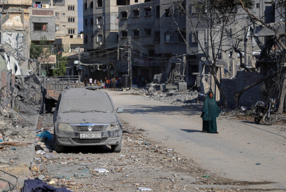 Seorang wanita Palestin berjalan melepasi bangunan yang musnah dalam serangan udara Israel di Gaza City, pada Rabu. - Foto Xinhua