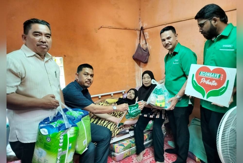 Mohamad Radhi (dua dari kiri) menyampaikan bantuan makanan dan kelengkapan untuk kegunaan Nor Syakinah kepada Teh (tiga dari kanan) di rumah mereka di Kampung Simpang Tiga Alor Binjal di sini pada Khamis.