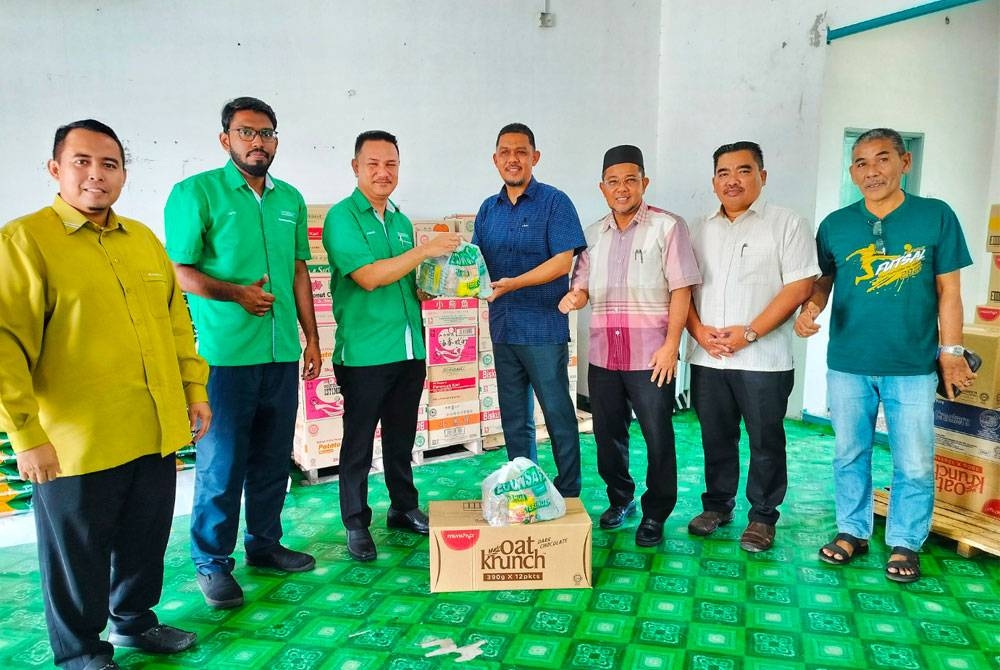 Zamzuri (tiga dari kiri) membuat simbolik penyerahan barangan keperluan sempena program CSR Econsave Prihatin kepada 150 keluarga dalam DUN Alor Mengkudu kepada Mohamad Radhi pada Khamis.