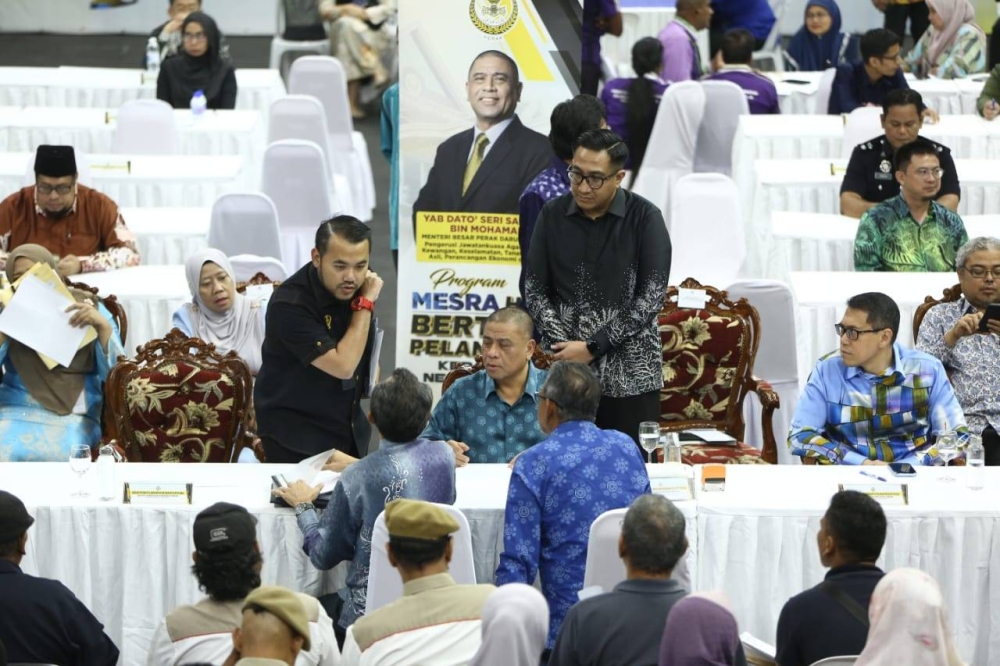 Saarani (duduk, kiri) melayani aduan rakyat ketika Program Mesra Bertemu Pelanggan Kerajaan Negeri Perak Siri ke-9 di Stadium Indera Mulia pada Khamis.