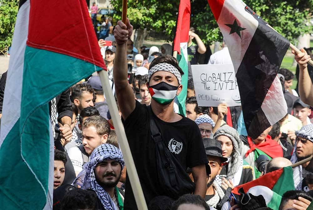 Orang ramai melaungkan slogan dan mengibarkan bendera kebangsaan Syria dan Palestin semasa perhimpunan sebagai solidariti dengan rakyat Palestin di Dataran Arnous di tengah Damsyik pada Selasa. - Foto AFP