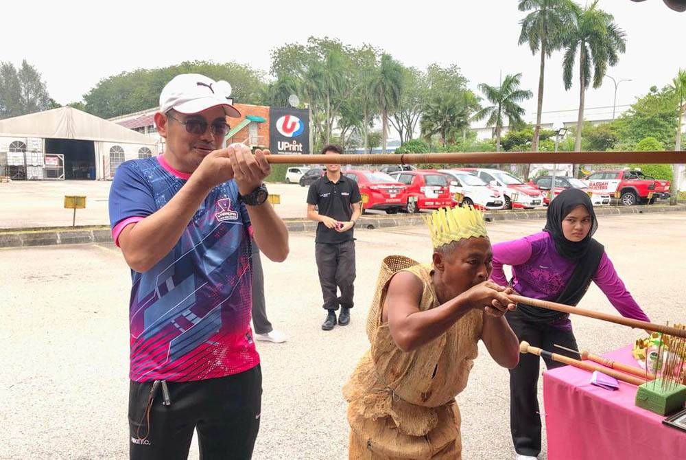 Pengunjung mencuba aktiviti menyumpit di gerai pameran Sumpit Orang Asli Mah Meri dari Pulau Carey.