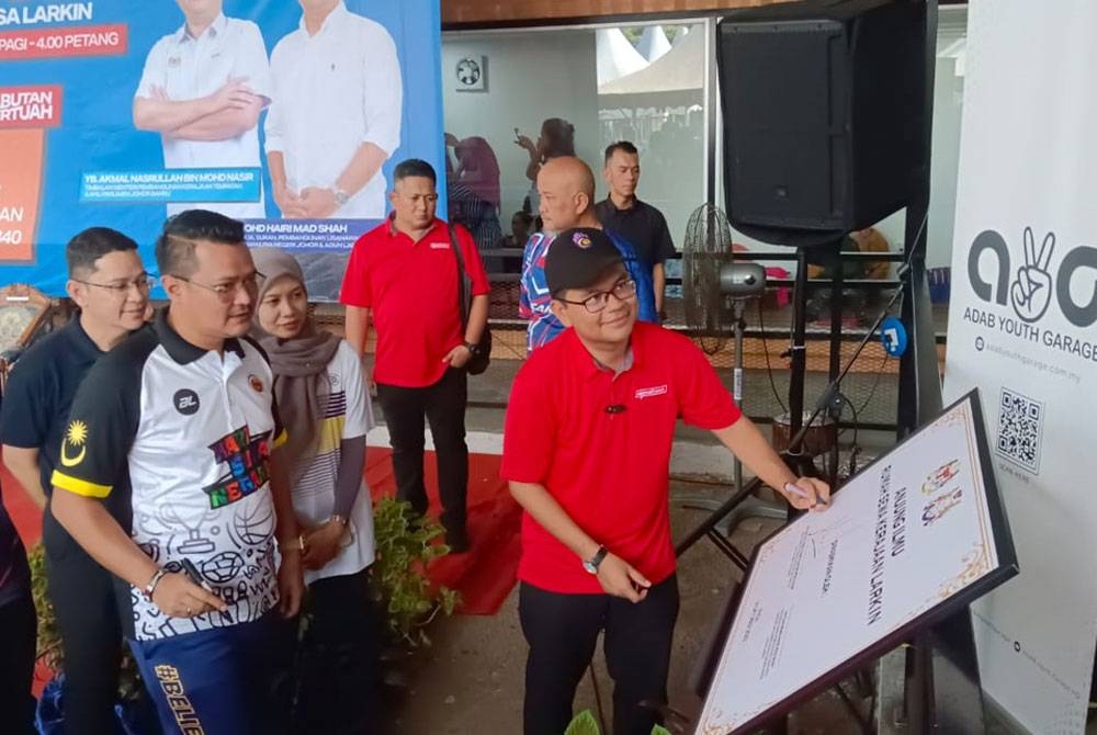 Akmal Nasrullah menurunkan tandatangan sebagai simbolik perasmian Anjung Ilmu selepas merasmikan Program Hari Sukan Negara di Rumah Pangsa Larkin, Johor Bahru pada Sabtu.