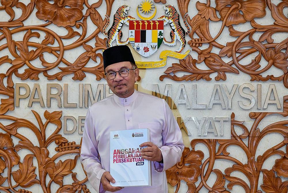 Anwar menunjukkan buku Anggaran Perbelanjaan Persekutuan 2024 yang dibacakan ketika membentangkan Belanjawan 2024 Malaysia MADANI di Parlimen pada Jumaat. Foto: Bernama