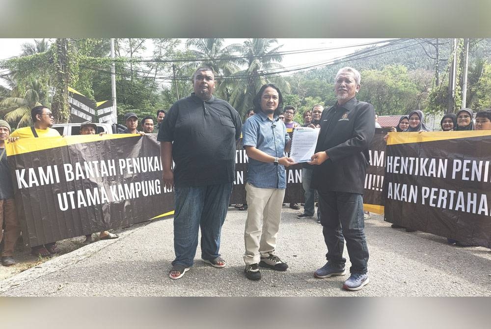 Faizal (tengah) menyerahkan petisyen bantahan kepada Mohd Maskor (kanan) selepas bantahan aman pendud Kampung Bukit Cherakah di sini pada Ahad.