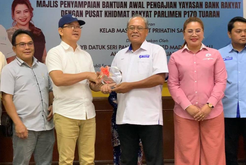 Wilfred (tiga dari kiri) menyampaikan hadiah penghargaan kepada Philip pada Majlis Perasmian Bantuan Awal Pengajian YBR di Dewan jubli Emas, Sekolah Menengah Kebangsaan Tamparuli, Sabah.