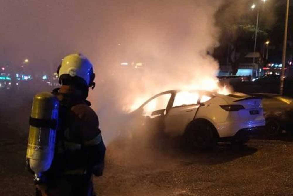 Anggota bomba memadamkan api pada kereta Tesla yang secara tiba-tiba terbakar di Jalan Puchong Jaya, Puchong, Selangor, malam tadi. - Foto Astro Awani