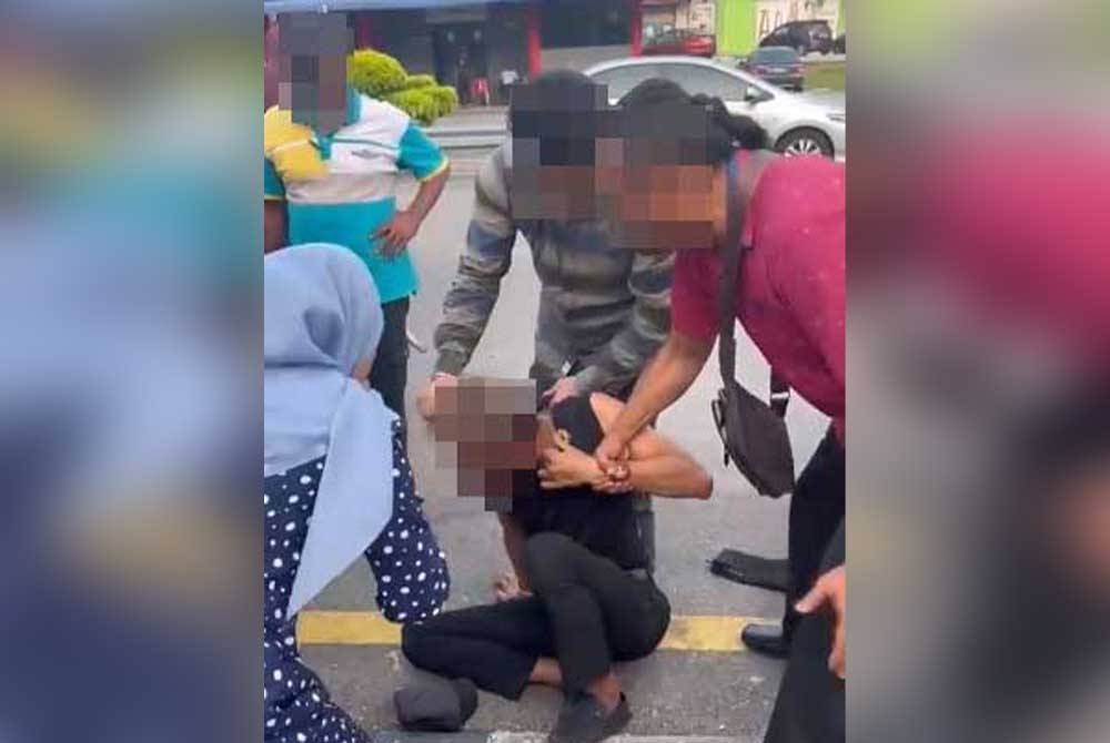 Wanita dipercayai mangsa ragut (kiri) cuba merakam wajah suspek setelah berjaya ditangkap oleh orang ramai pada Selasa. - Foto tular