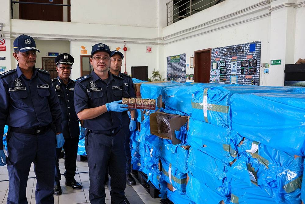 Mohd Nadzri (kanan) menunjukkan sebahagian rokok yang dirampas pada sidang media mengenai rampasan rokok di Pejabat Kastam Kemaman pada Rabu. - Foto: Bernama